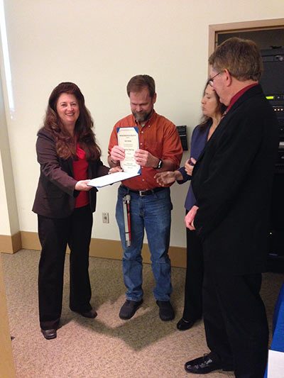 Andy receiving award surrounded by 3 people in business attire