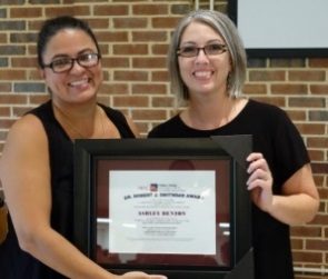 Two women holding a framed award between them