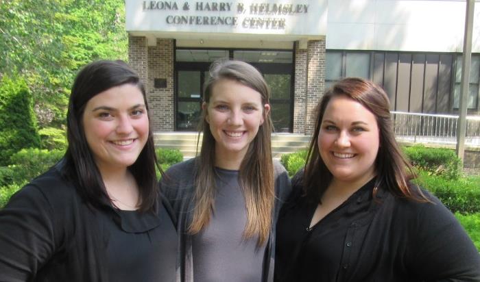 Three women job coaches smiling outside in front of a conference center building