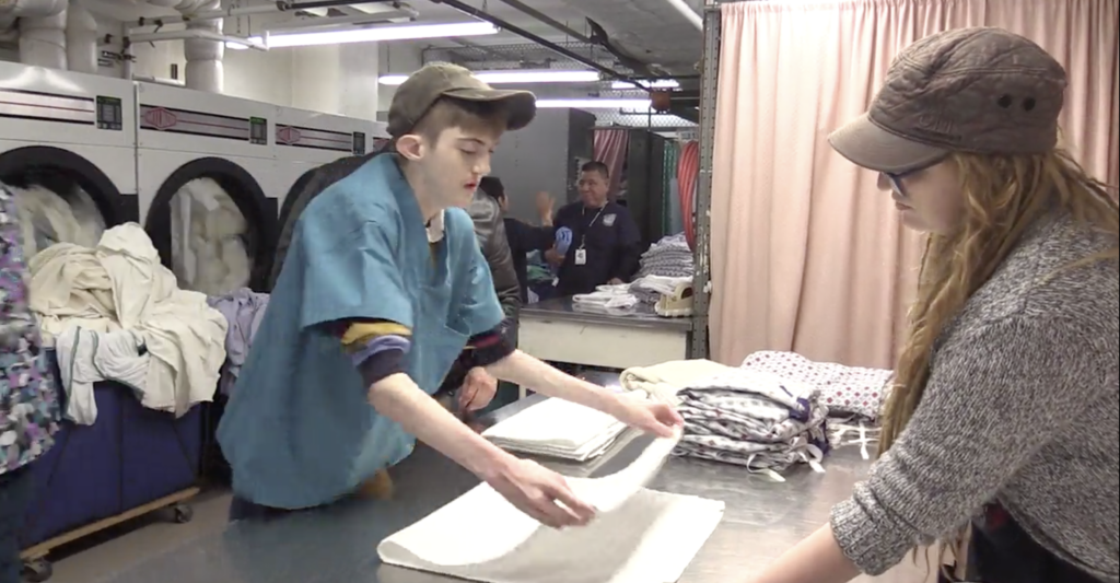 2 people folding towels at a laundromat