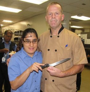 A girl and a man standing and holding a knife