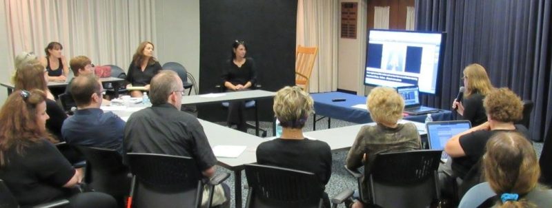 A group of people sitting around a table looking at a screen