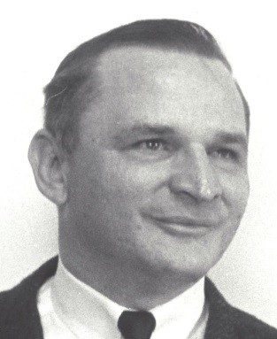 Robert J. Smithdas smiling and wearing a suit and tie