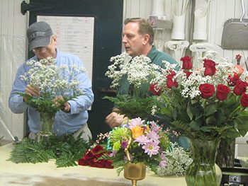 Two men standing and arranging flower bouquets 