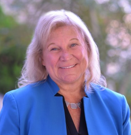 Sue Ruzenski smiling outside and wearing a light blue suit jacket