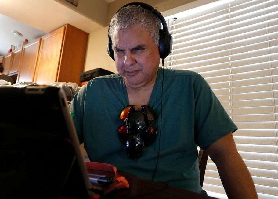 Robert Tarango wearing headphones and squinting at a computer screen