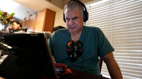 A man named Robert Tarango wearing headphones and looking at a screen