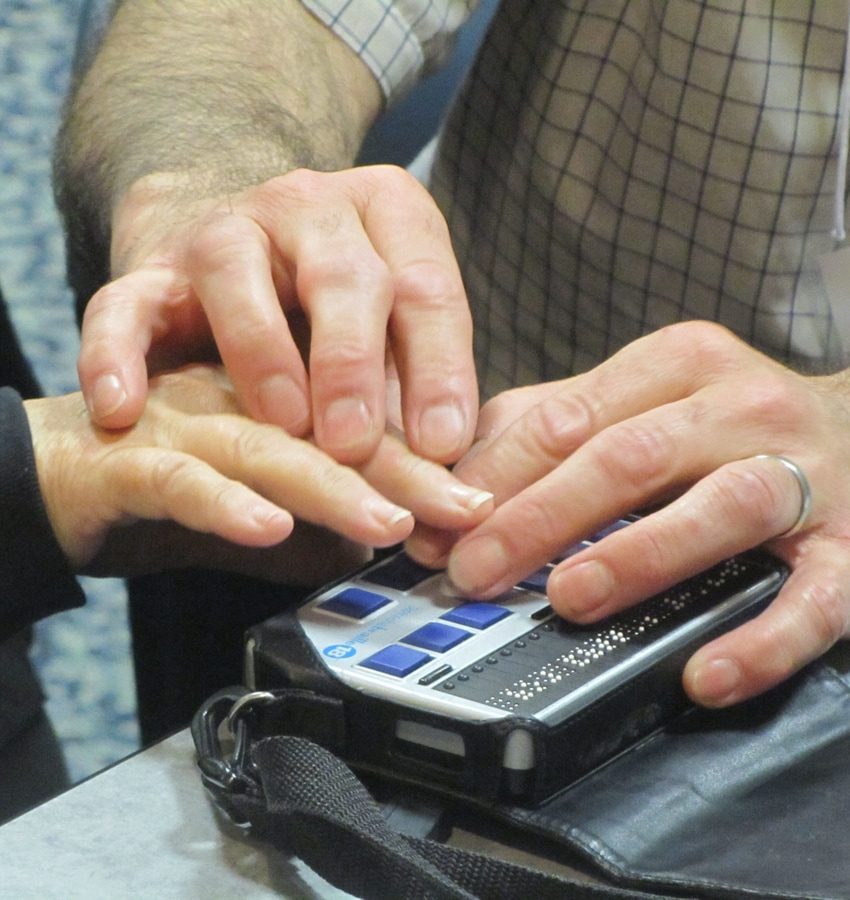 2 sets of hands touching a braille display 