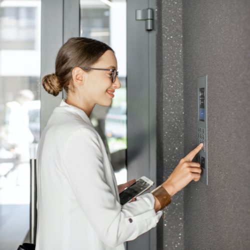 A woman holding her phone and dialing numbers on the wall.