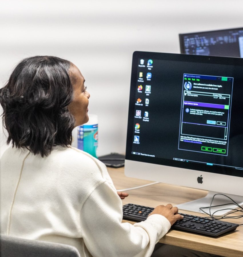 Woman sitting at desk looking at a system update popup on her computer screen 