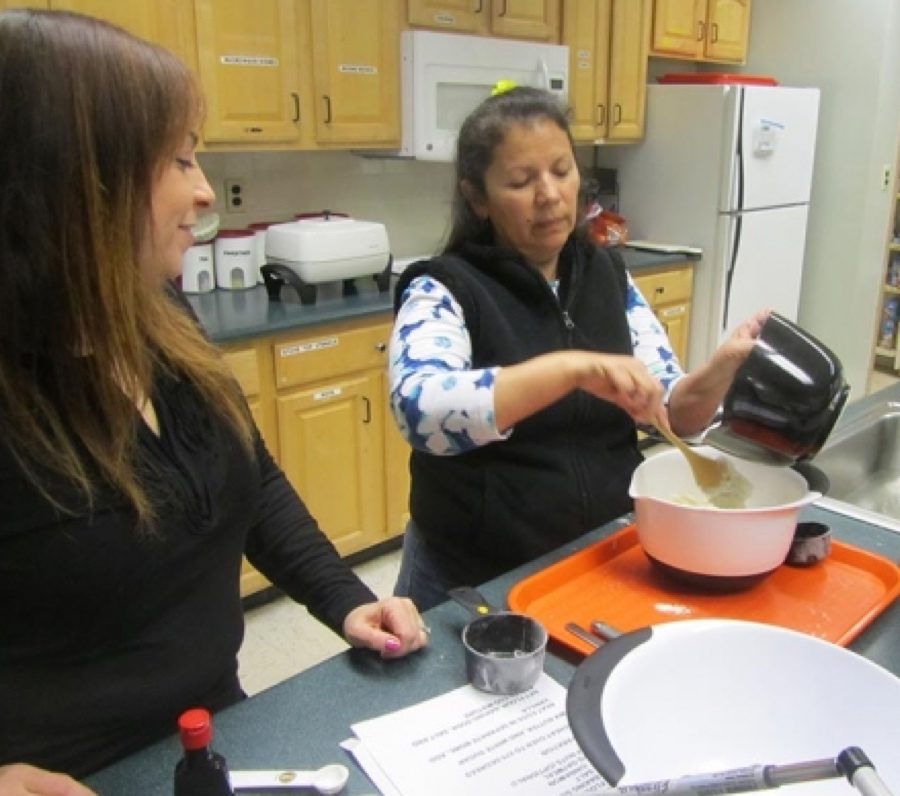 A woman cooking in a kitchen under supervision of another woman