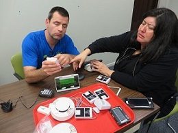 A man and a woman sitting at a table working with assistive devices