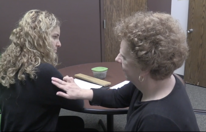 A woman touching another woman's shoulder with her right hand