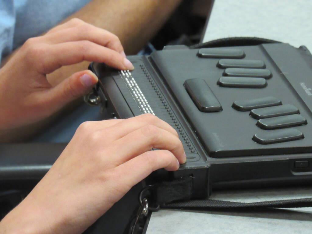 Hands touching a braille display