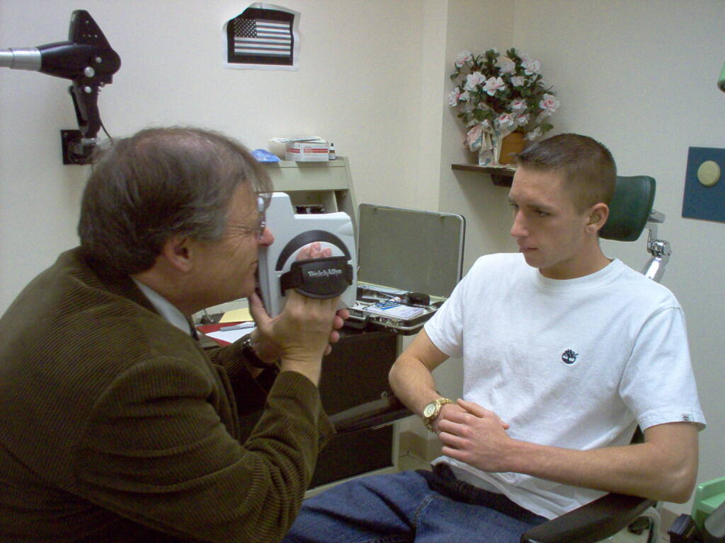 A man checking eyes of a young man in an office