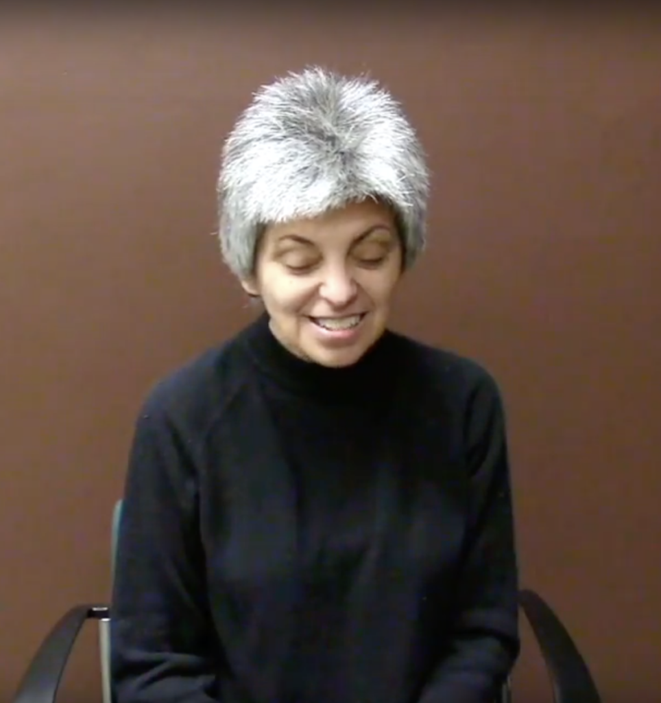 Woman with short white hair smiling and looking down