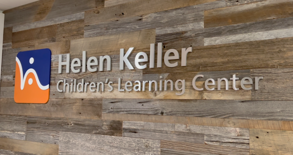 Helen Keller Children's Learning Center logo sign mounted on a wooden wall