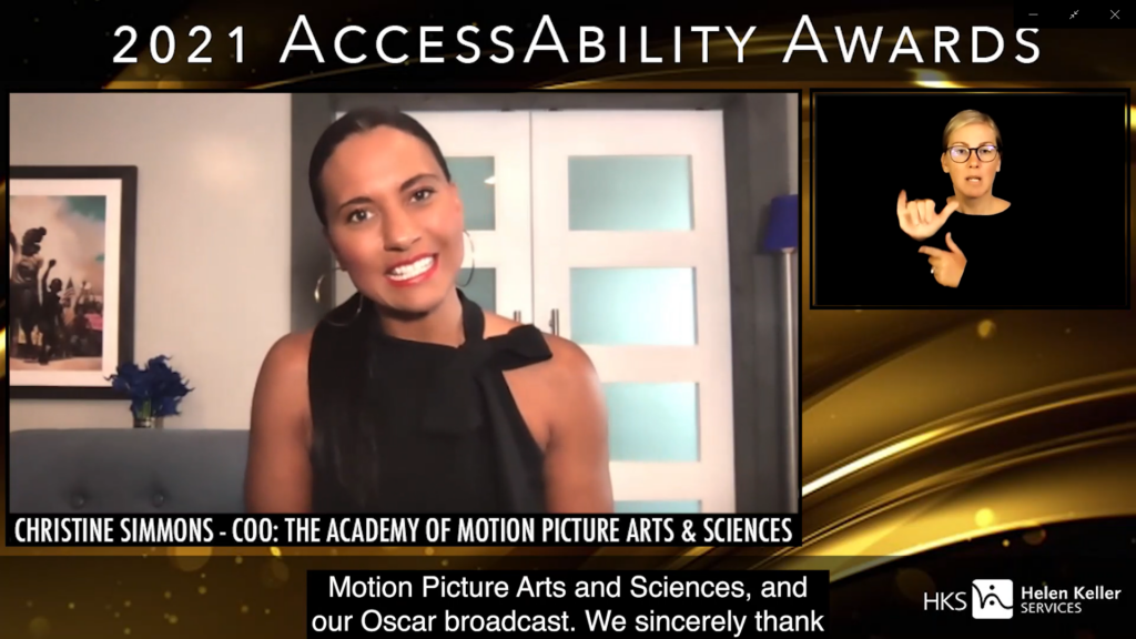 Woman smiling into camera and another woman signing. Text on image says “2021 Accessibility Awards”