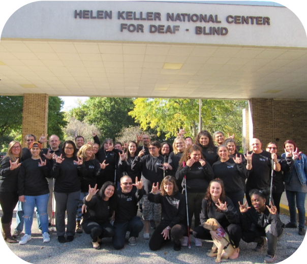 Group of people signing I Love You in front of the Helen Keller National Center