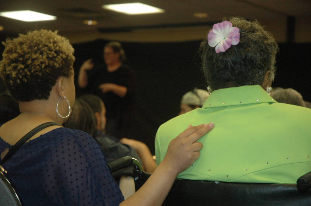 One woman touching another woman's back with three fingers