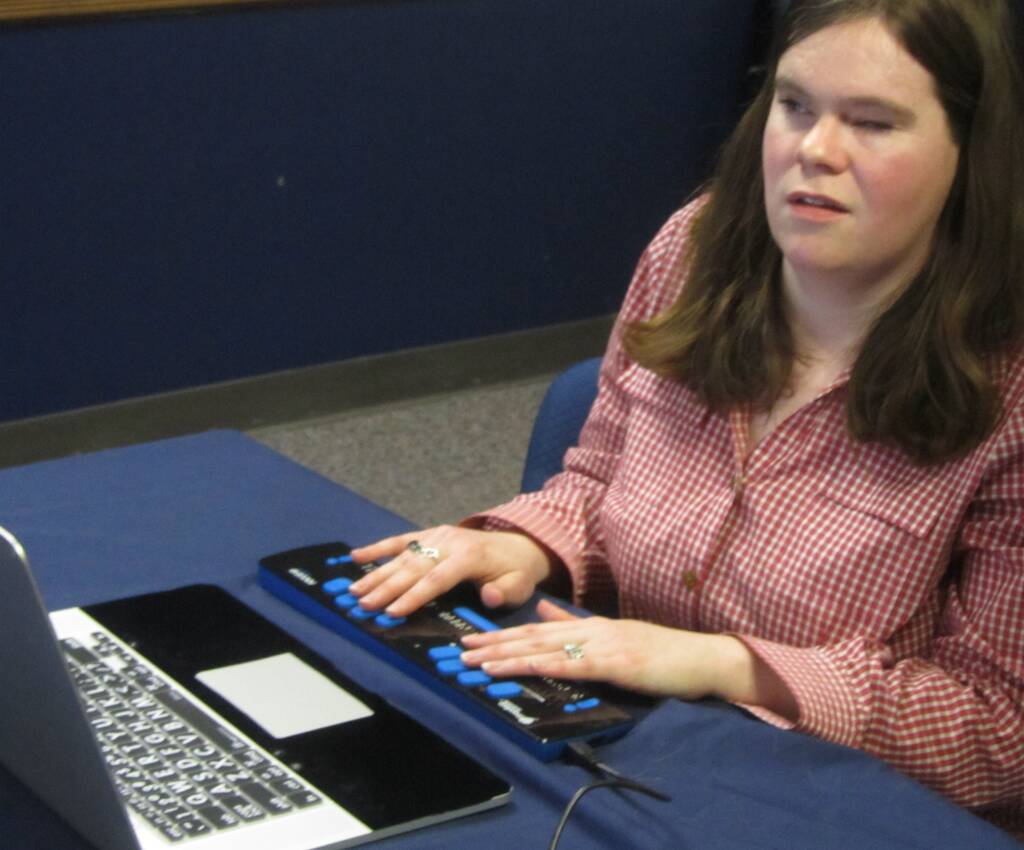 Woman using a braille display and a laptop
