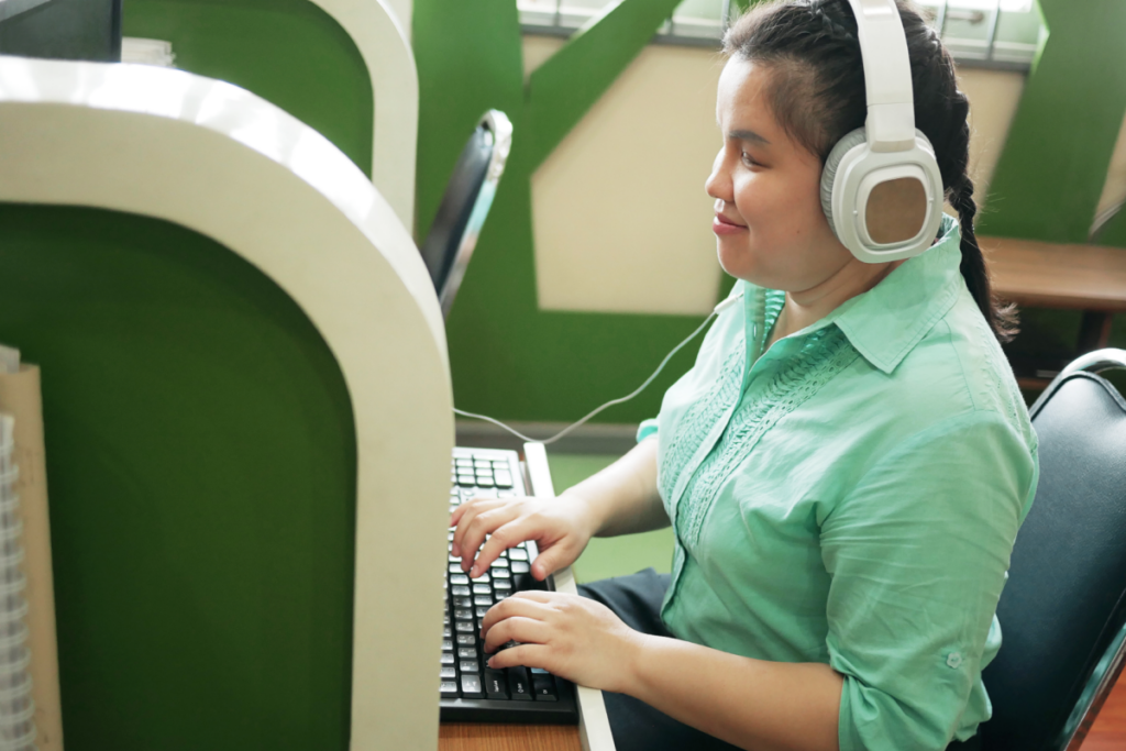 Woman wearing headphones and typing on a computer keyboard