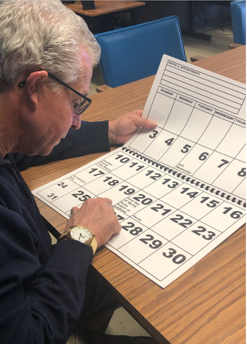An older man looking at a calendar with large numbers on it