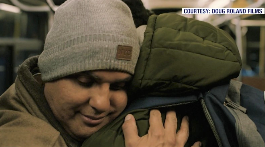 Two men wearing winter clothing hugging