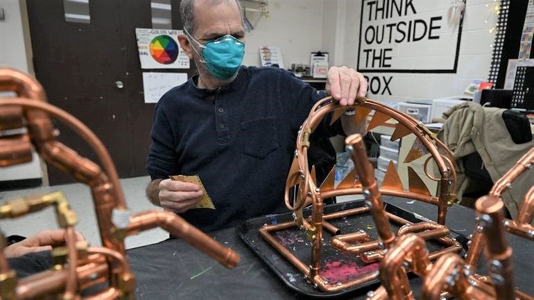 Tony Giordano touching his large copper sculpture of an open mouth with pointy teeth