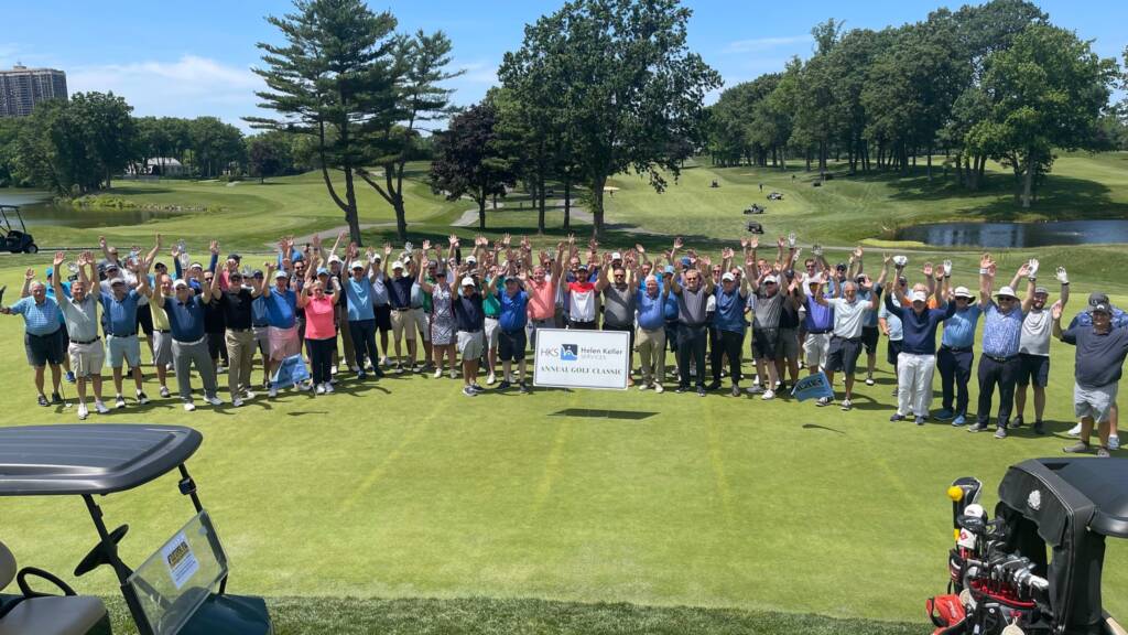 A large group of people raising their hands outside on a golf course