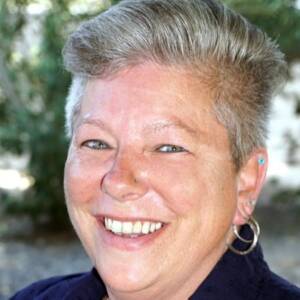 A white woman with short grey hair smiling outside