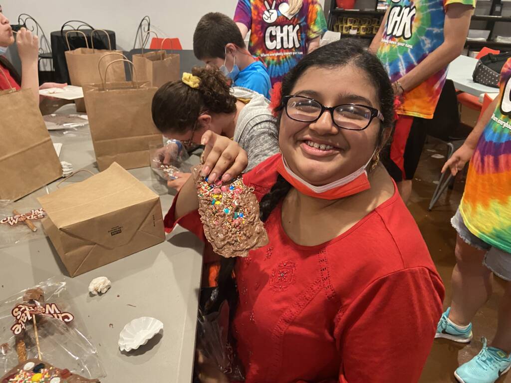 A girl smiling and holding a food item with M&Ms in it