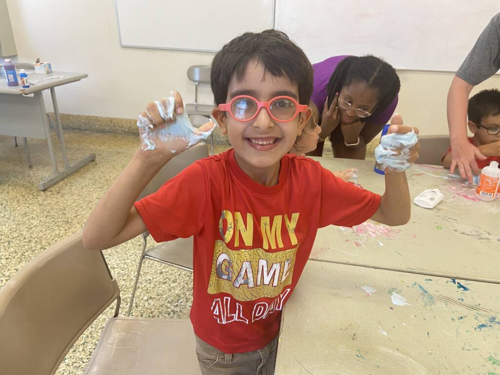 A boy holding his hands up showing a soapy substance on both hands