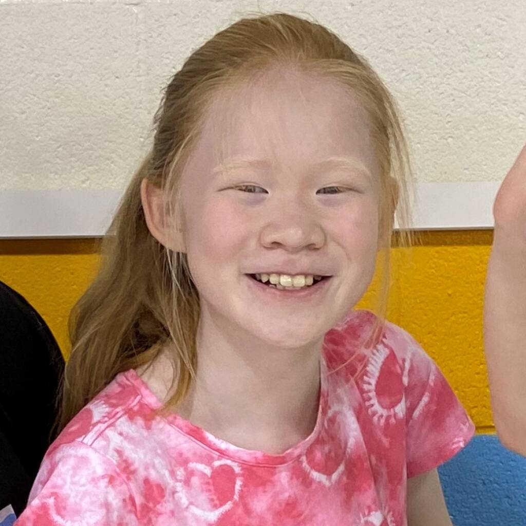A young girl with red hair smiling into the camera