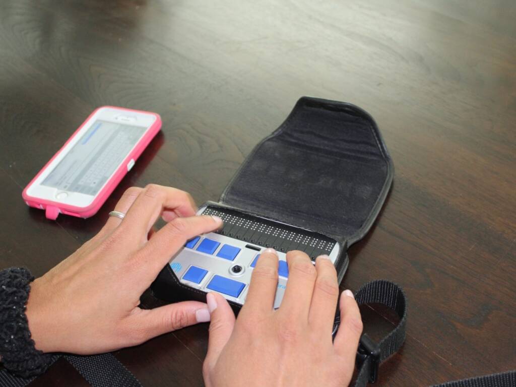 A close up of someone's hands touching the keys of a braille display