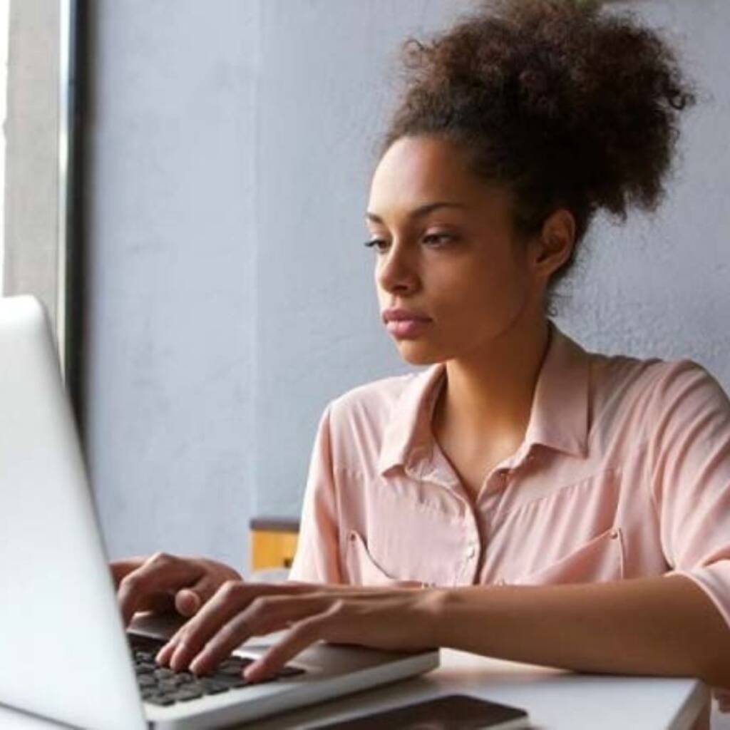 a dark skinned woman typing on a laptop