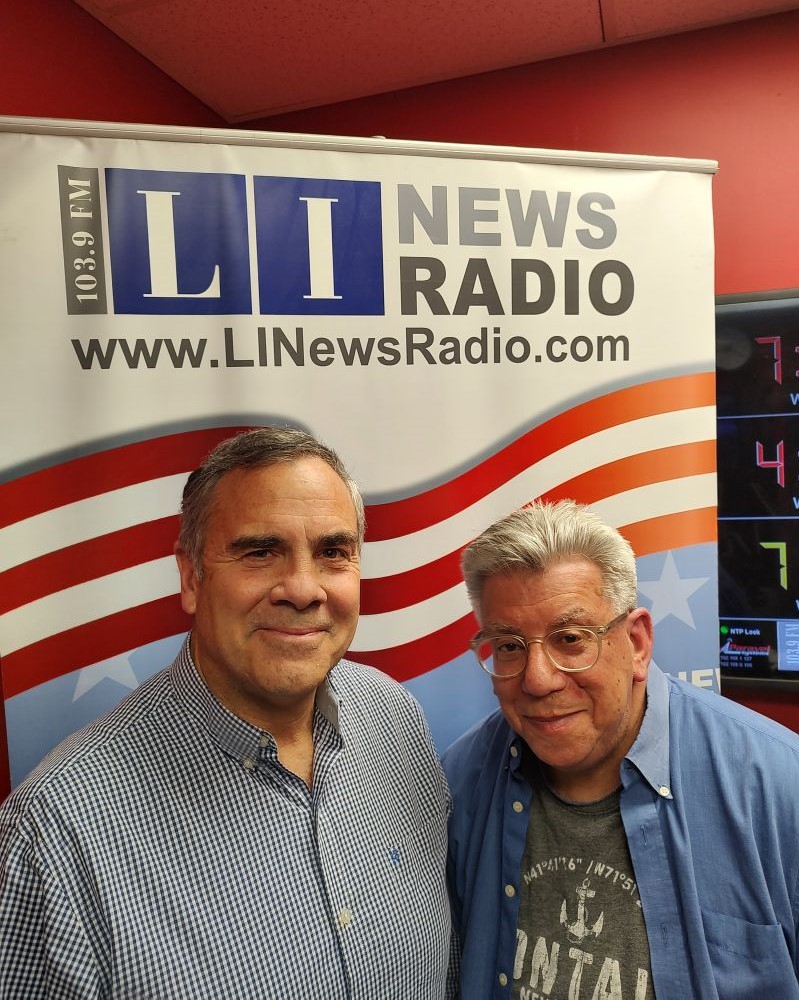 Joe Melillo and Scott Passeser smiling in front of a LI News Radio sign.