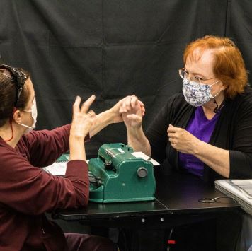 two women touch hands and sign