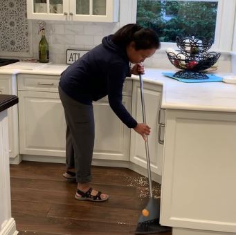 a DeafBlind woman sweeps a kitchen floor