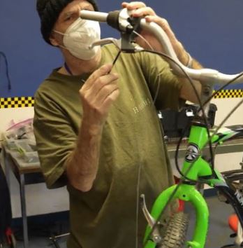 a DeafBlind man works on the handlebars of a bicycle