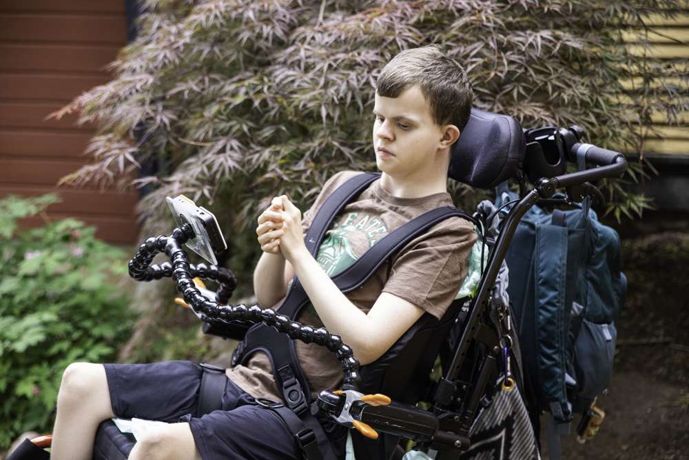 A DeafBlind man sits in an adaptive wheelchair while managing music