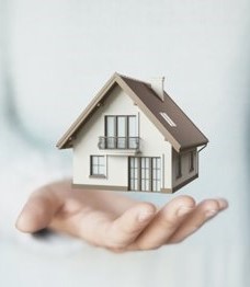 a small model of a home hovering on top of someone's hand