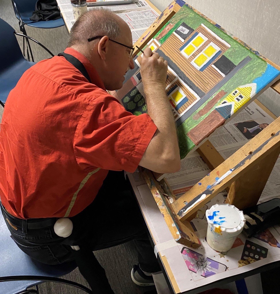 a man painting a house on a canvas with acrylics