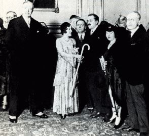 Guilly d’Herbemont holding a cane in the middle of a group of people