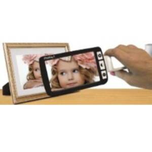 A black handheld magnifier being held in front of a picture frame. On the magnifier is an enlarged image of a photo of a young girl with a large light pink flower in her hair