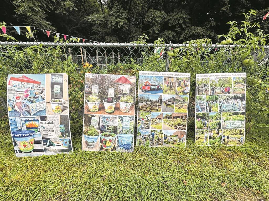4 large posters learning up against a garden's fence. On the posters are several garden photos.