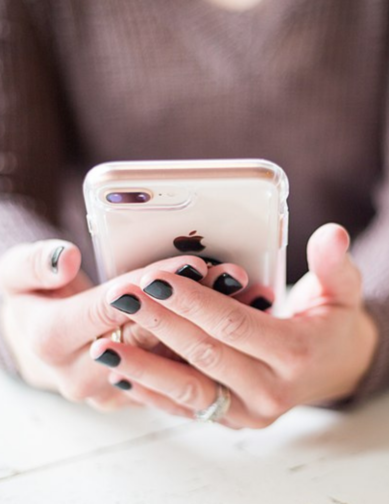 a close up of someone's hands holding an iPhone