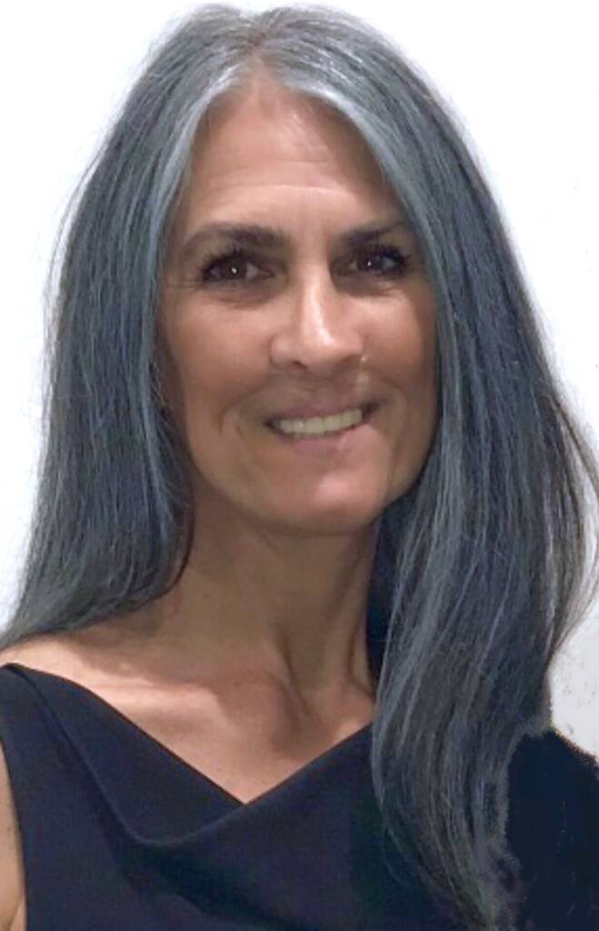 A woman named Robin with long silver hair smiles into the camera