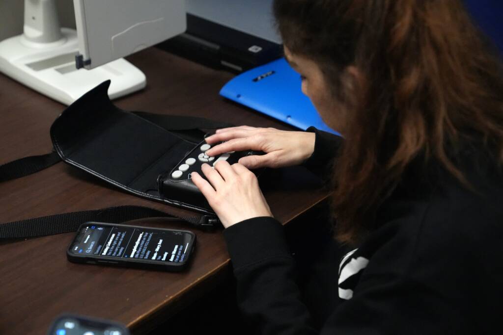 A woman using a braille display that's connected to an iPhone