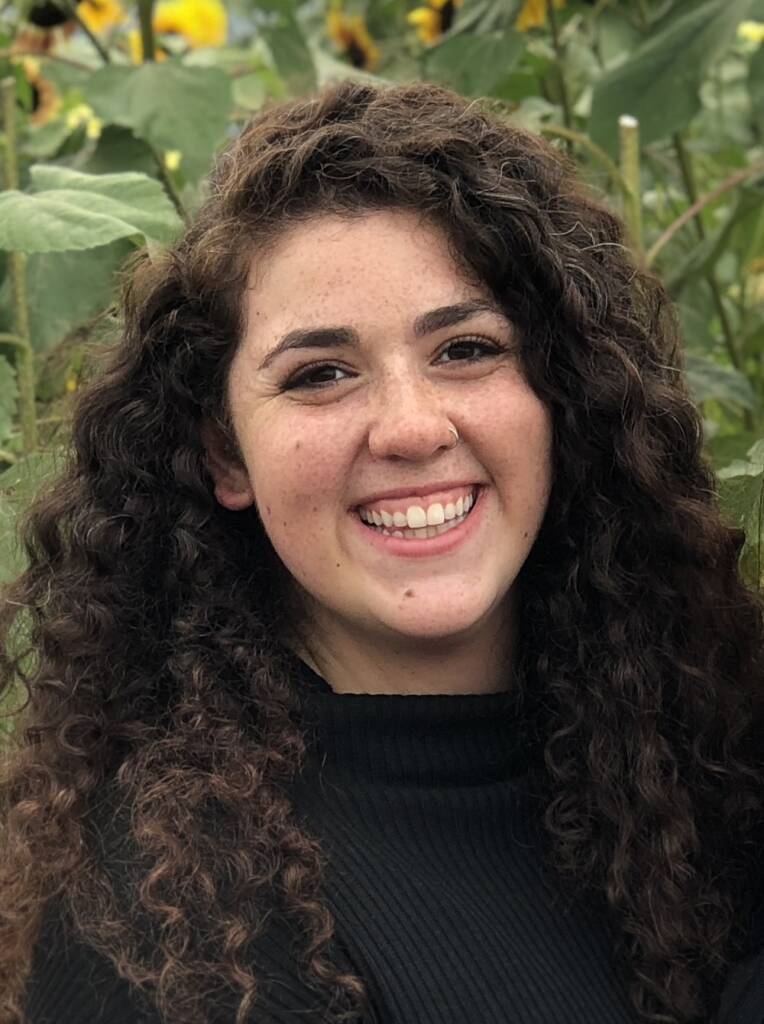 A woman named Leanne with long and curly brown hair smiles into the camera